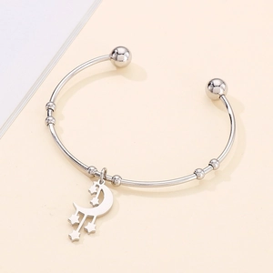Detail of silver crescent moon and star charms on an adjustable stainless steel cuff bracelet