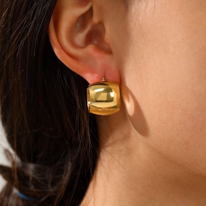 Close-up of polished 14K gold plated chunky cylinder hoop earrings on a female ear