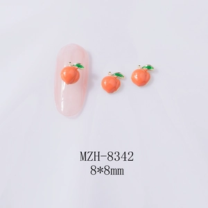 Macro detail of 8x8mm peach-shaped alloy nail charms with pink resin and green leaves