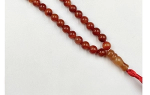 Close-up of polished red agate beads with a traditional red woven knot detail