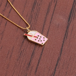 Détail du collier en chaîne dorée avec pendentif bubble tea rose et paille rouge