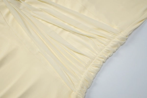Detailed close-up of cream yellow ruched fabric texture on a slim-fit evening dress