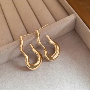 Minimalist wavy flame gourd earrings in polished gold finish on velvet display