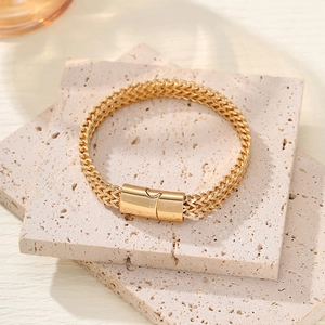 Detail of gold wheat chain bracelet with magnetic clasp on beige travertine stone base