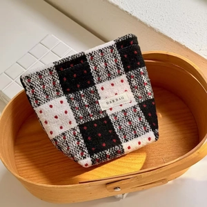 Macro detail of plaid tweed cosmetic bag with red polka dots and woven brand label