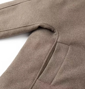 Detailed view of camel double-breasted jacket pocket stitching and wool-like texture