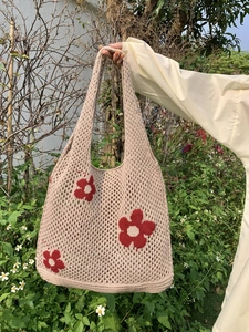 Detail der Strickstruktur einer khakifarbenen Tragetasche mit roten Blumenstickereien