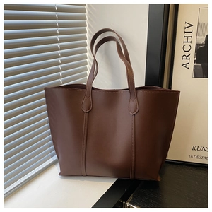 Close-up of a large brown leather tote bag with elegant vertical stitching and a soft texture