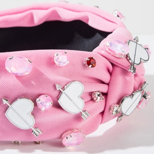 Detail of pink fabric headband with rhinestone accents and heart arrow embellishments