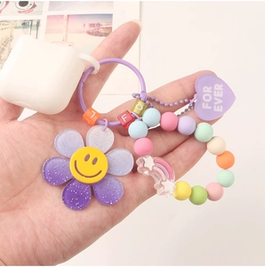 Detail of colorful sunflower keychain with rainbow bead bracelet on AirPods case