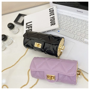 Detail of quilted cylinder bags in black and purple with gold chain and pearl accents