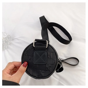 Detail showing 3D textured fabric and black wide nylon shoulder strap of the round bag