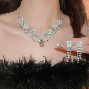 Elegant floral rhinestone necklace and teardrop pearl earring set on a model