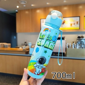 Detail view of 700ml blue astronaut water bottle held in a cozy cafe setting