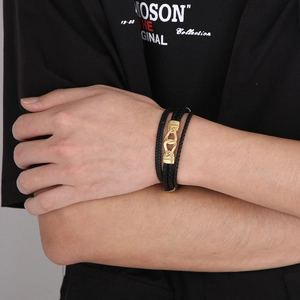 Détail du bracelet multicouche en cuir noir avec fermoir magnétique doré gaufré