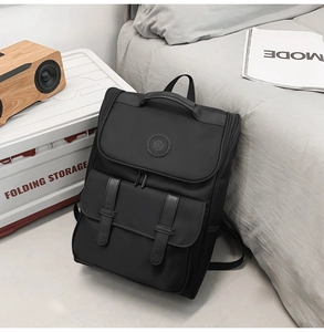 Minimalist black nylon backpack with leather accents placed in a modern room setting