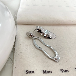 Detailed view of silver asymmetric geometric earrings with molten lava design on canvas