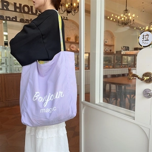 Detail of lilac nylon tote bag with Bonjour print and yellow green plaid strap