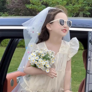 Detail of a white mesh veil with colorful pom-poms for girl birthday parties