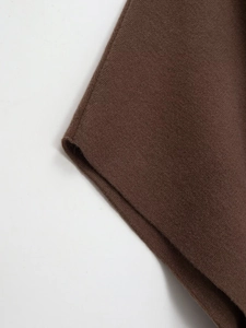 Macro shot showing the detailed knit texture and soft fibers of the dark brown poncho