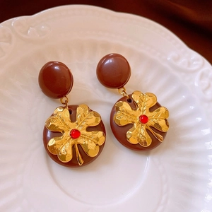 Nahaufnahme von Vintage-Blumenohrringen in Braun auf einem geprägten Keramikteller
