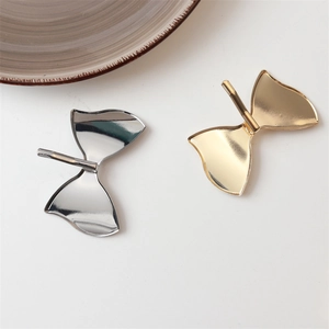 Detailed view of bow-shaped metallic hair clips in polished gold and silver finishes