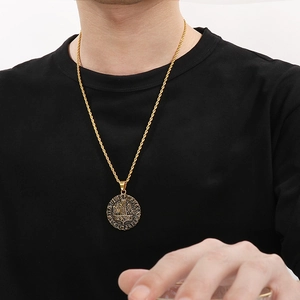 Dettaglio del ciondolo Mjölnir dorato con rune nordiche su una catena a maglia ritorta