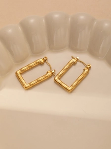 Macro shot of gold bamboo textured rectangular hoop earrings on a textured tray