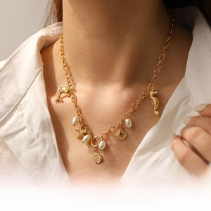 Detail of gold chain necklace featuring sea star, shell, and seahorse charms on a model