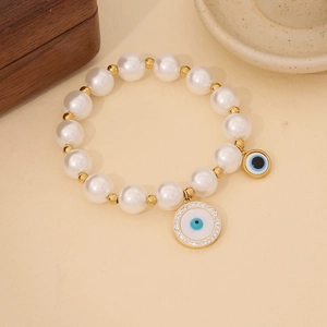 Detailed view of white pearl bead bracelet with evil eye charms and gold spacers
