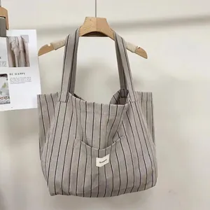 Detail of grey striped canvas tote bag with front pocket and functional brand label