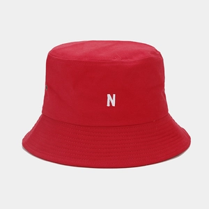 Détail d'un chapeau bob en toile rouge avec broderie lettre N blanche et œillets en métal