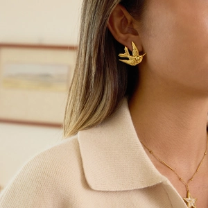 Boucles d'oreilles oiseaux en acier plaqué or 18K portées par un mannequin chic