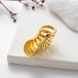 Macro detail of multi-layer hollow golden finger armor ring on white textured base