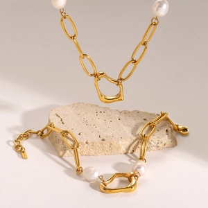 Detail of 18k gold plated steel necklace and bracelet set with white pearls on stone