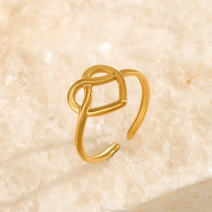 Anello aperto minimalista a nodo di cuore dorato da donna su sfondo di pietra ruvida