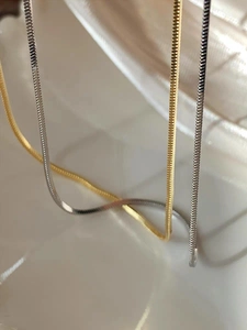 Detalle macro de cadenas de serpiente planas en oro y plata con textura pulida