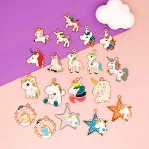 Macro shot of colorful enamel unicorn charms with gold plating on a purple and pink background