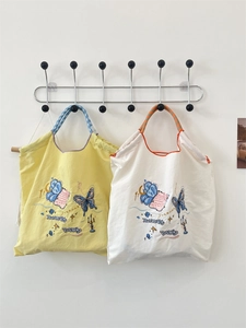 Close-up of butterfly embroidery on vintage canvas tote bags with striped handles