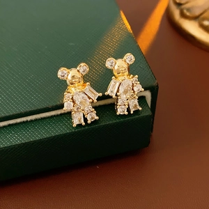 Macro shot of gold-plated bear stud earrings with zircon stones on a green jewelry box