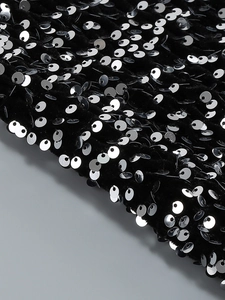 Vue détaillée des paillettes argentées sur le tissu en velours noir de la robe