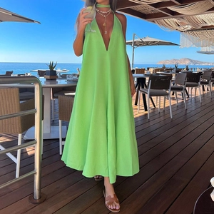 Detail of bright green V-neck halter maxi dress featuring natural linen texture on a beach