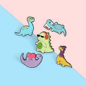 Flat lay of five colorful cartoon dinosaur enamel pins on a pink and blue background
