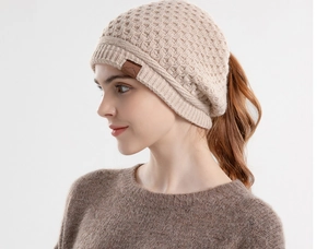 Detail showing the beige cable knit texture and ponytail hole design of the winter beanie