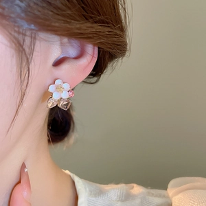 Close-up of flower stud earrings with white shell petals and pink crystal pendants