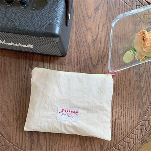 Close-up of cream macaron makeup bag with pink zipper on a wooden table setup