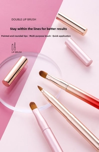 Close-up of double-ended retractable lip brushes with protective caps in pink and gold
