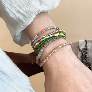 Detail of bohemian layered colorful seed bead bracelets worn on a model's wrist