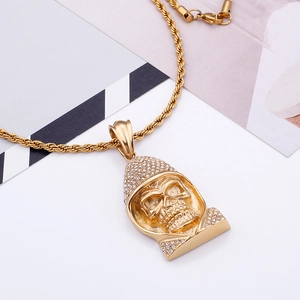 Detail of a golden skull pendant with sparkling diamonds and a twisted rope chain