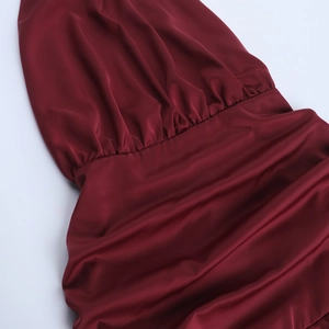 Detail of burgundy satin dress showing elastic pleated waist and draped fabric texture